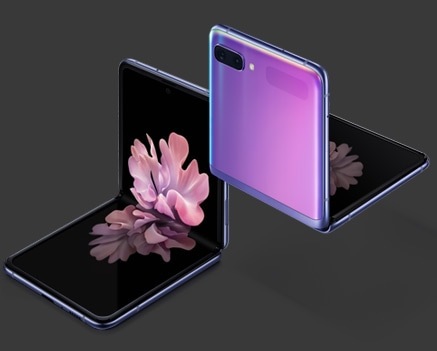 هاتفان طراز Galaxy Z Flip يظهران باللون الأرجواني العاكس بزاوية ثلاثة أرباع؛ أحدهما معروض من الجهة الأمامية والآخر من الجهة الخلفية. وكلاهما مطويان بزاوية قائمة بفضل تقنية الطي الحر. ويعرض الهاتف الظاهر بجانبه الأمامي خلفية زهرة متفتحة على شاشته