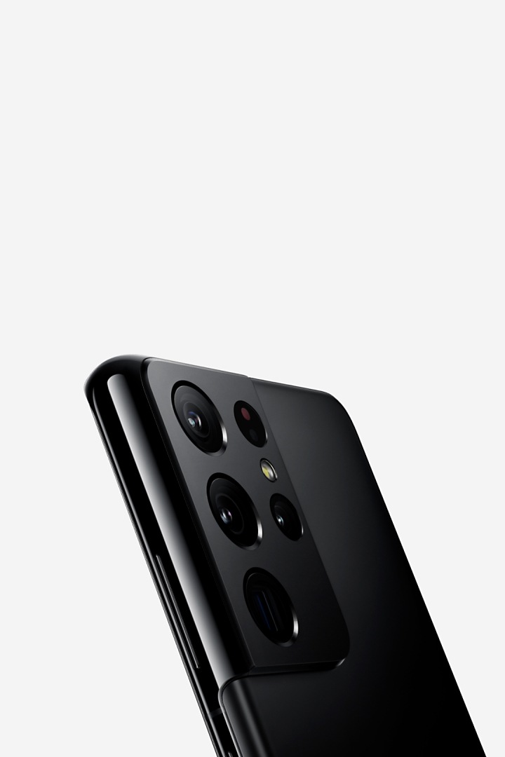 O telefone Galaxy S21 Ultra 5G em Phantom Black com um papel de parede gráfico vermelho no ecrã desliza pelo ecrã passando por outro telefone Galaxy S21 Ultra 5G em Phantom Black. Conforme se move pelo ecrã, o telefone ao fundo gira, revelando quatro câmaras traseiras.