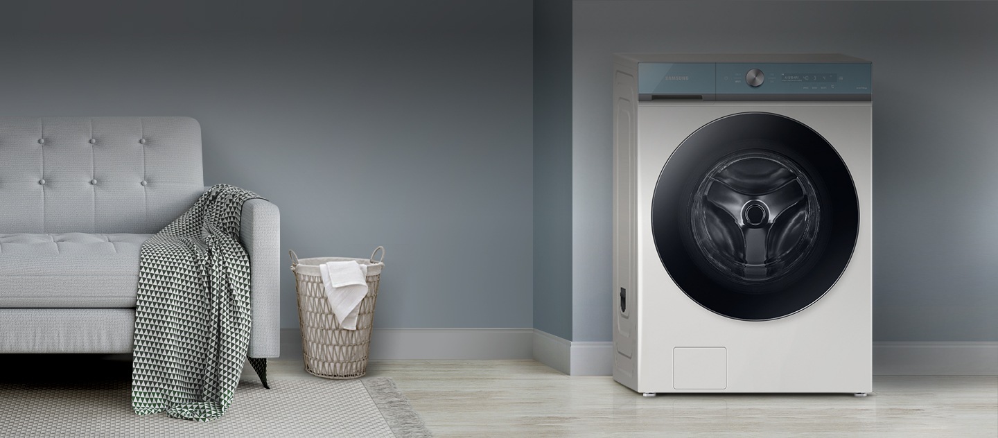 Se muestra una lavadora inteligente en el lado derecho y un sofá, un canasto de lavandería y ropa para lavar en el lado izquierdo.