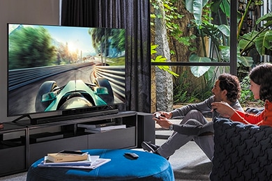 Un hombre joven juega en el televisor QLED. Los jugadores pueden mejorar al máximo su experiencia de juego con la pantalla grande y la calidad de imagen 4K con HDR.