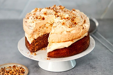 Pastel esponjoso de café cubierto con merengue, avellanas y crema batida fresca.