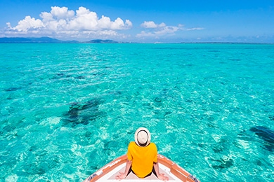 na imagen de un hombre sentado en un barco que observa el mar azul durante sus vacaciones en la playa.
