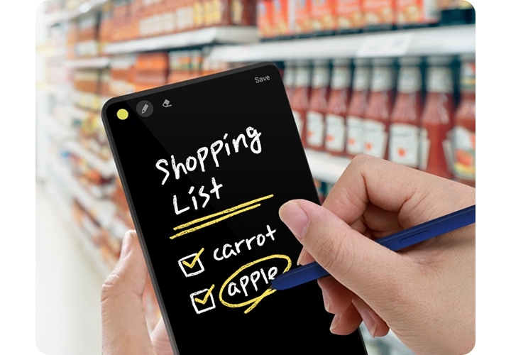 A closeup view shows a person in a supermarket holding a phone and S Pen. The phone screen shows the handwritten text 