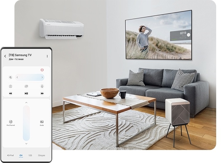 Гостиная с кондиционером на стене и очистителем воздуха Cube Air Purifier, который стоит рядом с журнальным столиком в центре комнаты. За столиком находится диван, а над диваном 65-дюймовый QLED-телевизор Q7, закрепленный на стене. Слева на переднем плане на экране Galaxy показан пульт ДУ Smart TV.