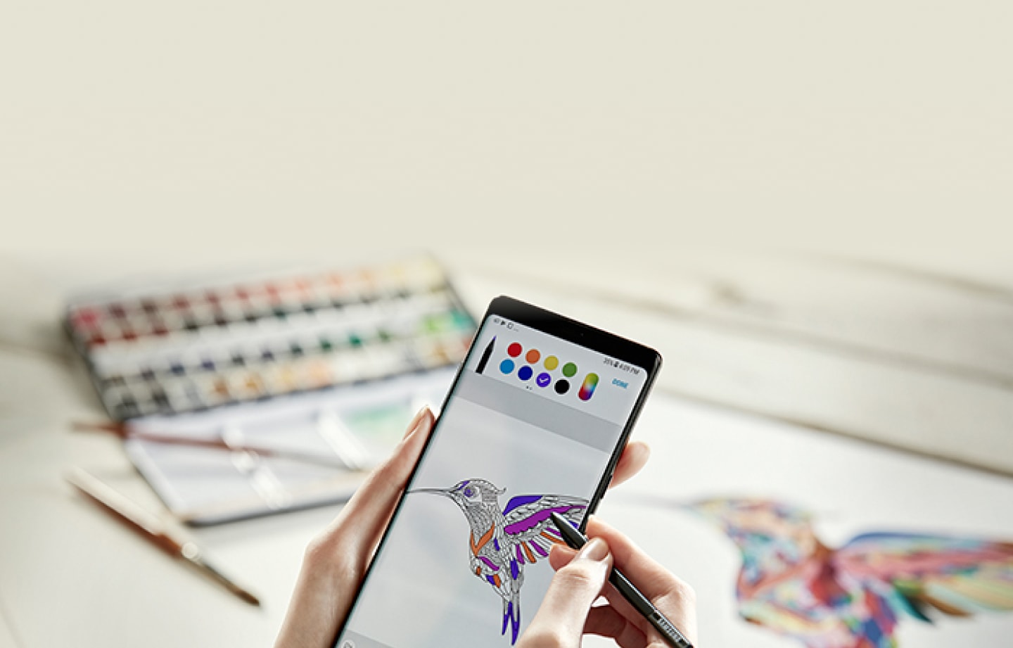 По отзывам, телефон Самсунг Нот 8 с поддержкой стилуса S Pen предлагает широкие возможности для творчества. Женщина рисует колибри рукой на экране телефона Нот8.