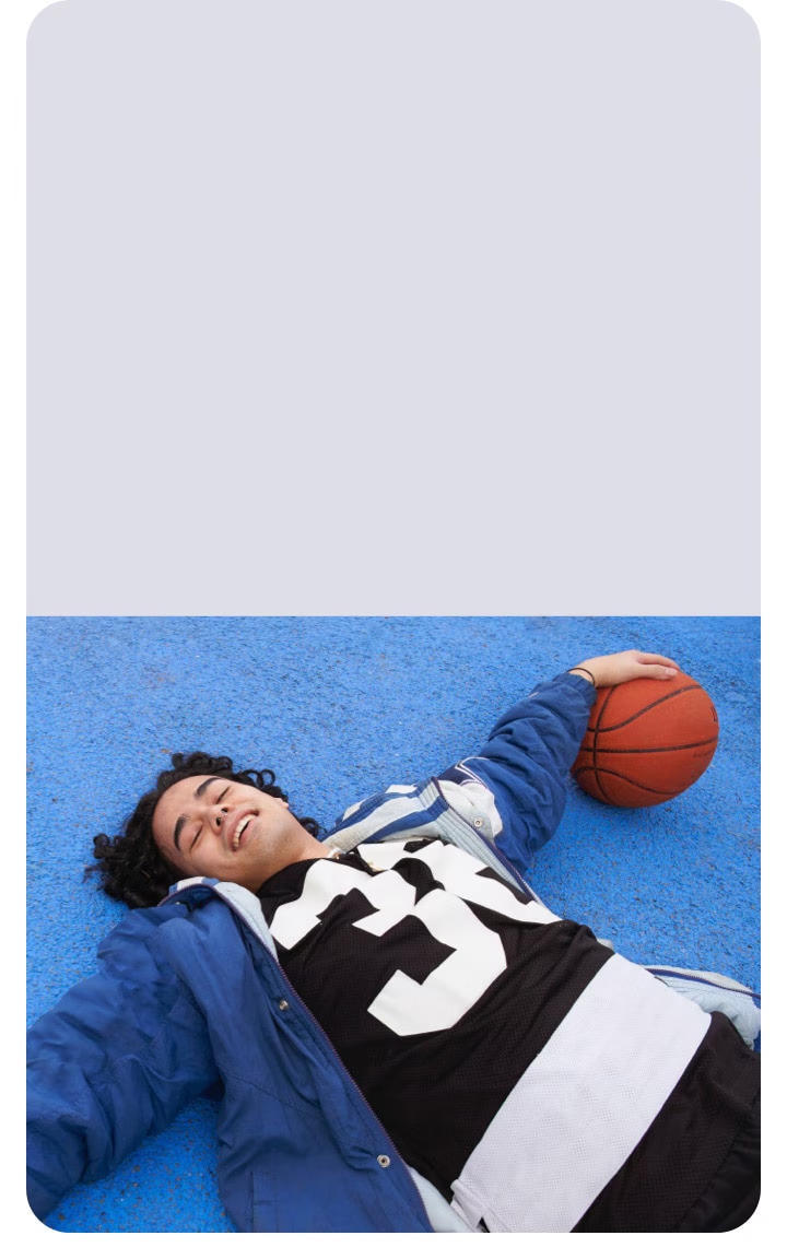 Парень в синей куртке лежит на баскетбольной площадке с мячом в руке, Galaxy Watch и Buds для любителей фитнеса и тренировок