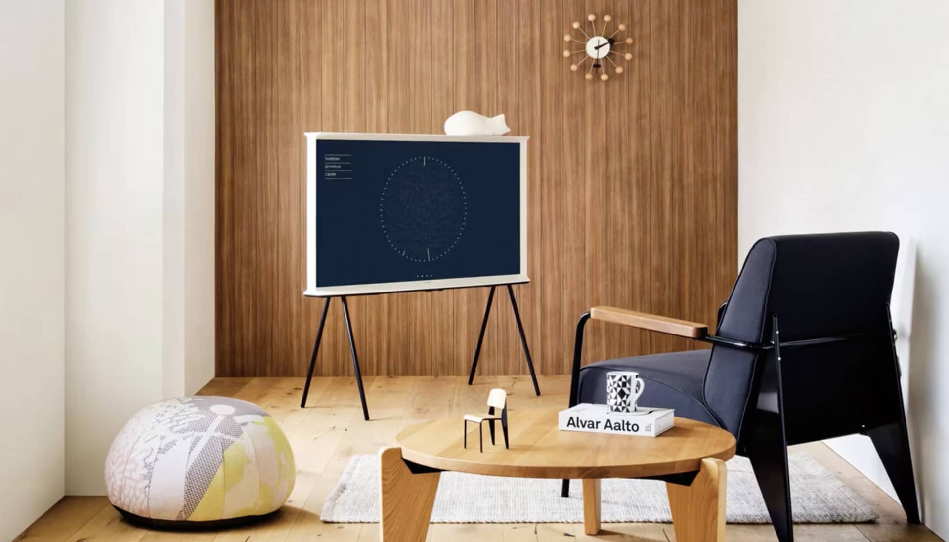 Белый телевизор The Serif в интерьере с деревом перед тёным креслом