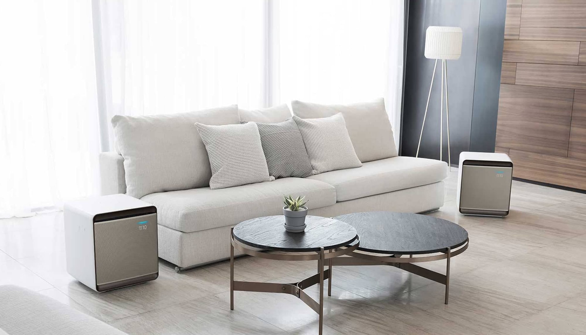 Два белых очистителя воздуха WindFree в гостиной рядом с диваном очищают воздух от пыли и аллергенов