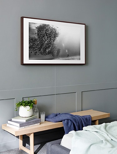 The Frame with the Invisible Connection on the wall above a bench opposite the bed in bedroom.