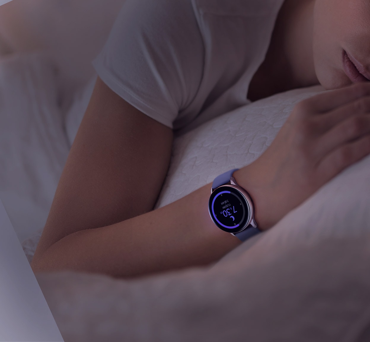 A person asleep wears the Rose Gold Galaxy Watch Active2. The watch face shows their sleep pattern compared to users in their age bracket.