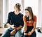 A man showing a woman how the theme on his Galaxy Watch matches with the theme on his smartphone.