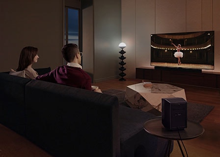 A couple enjoys a movie night in their living room with Samsung Soundbar's theater-like surround sound.