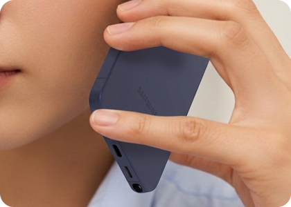 A hand holding a Samsung Galaxy phone with a finger covering the bottom microphone.