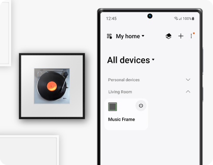 A Samsung Galaxy phone displaying the SmartThings app is positioned next to a Samsung Music Frame