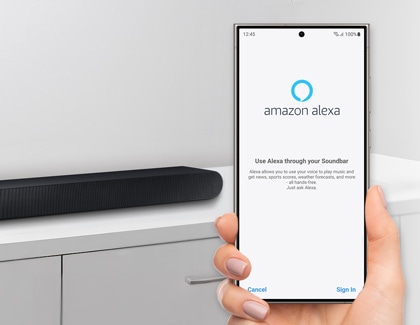 A person holding a Galaxy phone displaying the Amazon Alexa app sign-in screen, with a Samsung soundbar in the background.