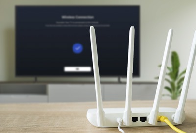 Router with cables connected, placed on a table in front of a Samsung Smart TV displaying a network connection screen.