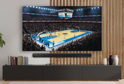 A Samsung Smart TV displaying a basketball game with a Samsung soundbar below, set in a modern living room.