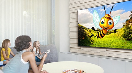 ครอบครัวหนึ่งกำลังดู YouTube อยู่ใน Samsung Smart TV ขณะอยู่ในห้องนั่งเล่น ภาพแอนิเมชันสามมิติที่เป็นตัวละครผึ้งนั้นถูกสตรีมอยู่ผ่านแอป YouTube ใน Smart TV.