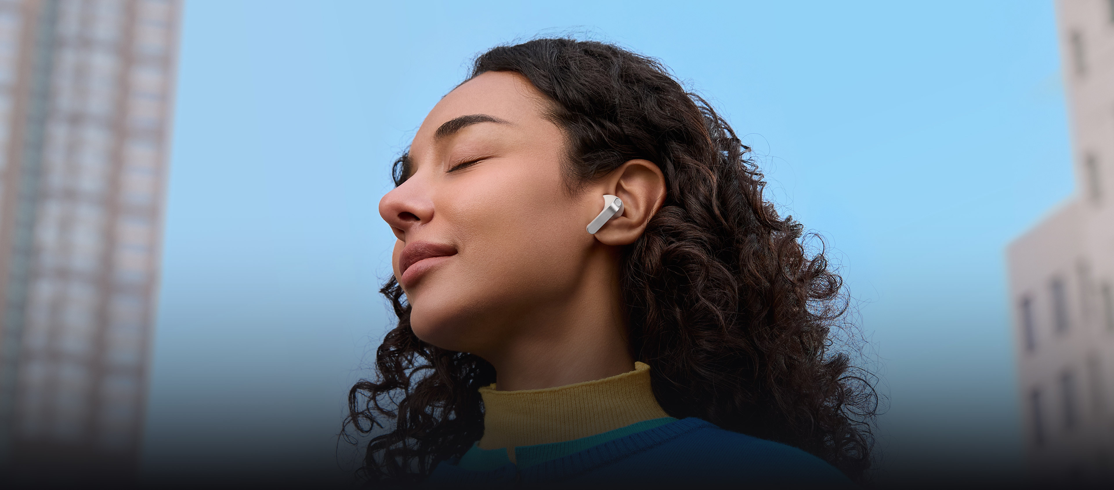 一名女性的耳朵上戴著單個極光白 Galaxy Buds4 Pro 耳機。