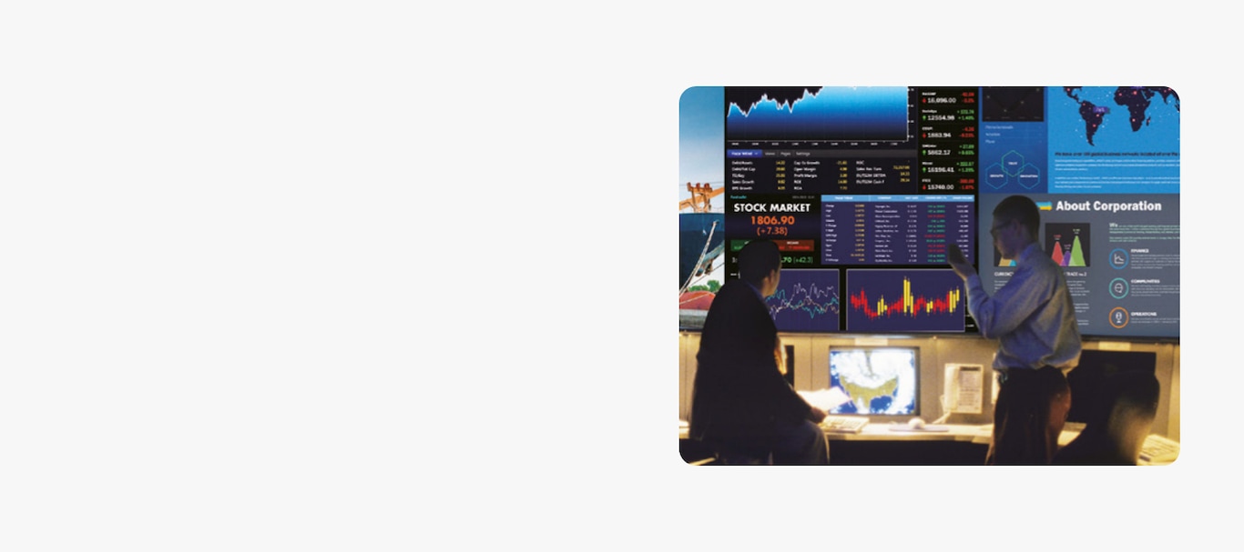 An image of two people talking where various financial indicators are being shown through The Wall.