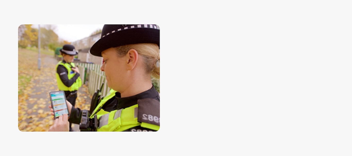 An image of a police officer holding a cell phone.