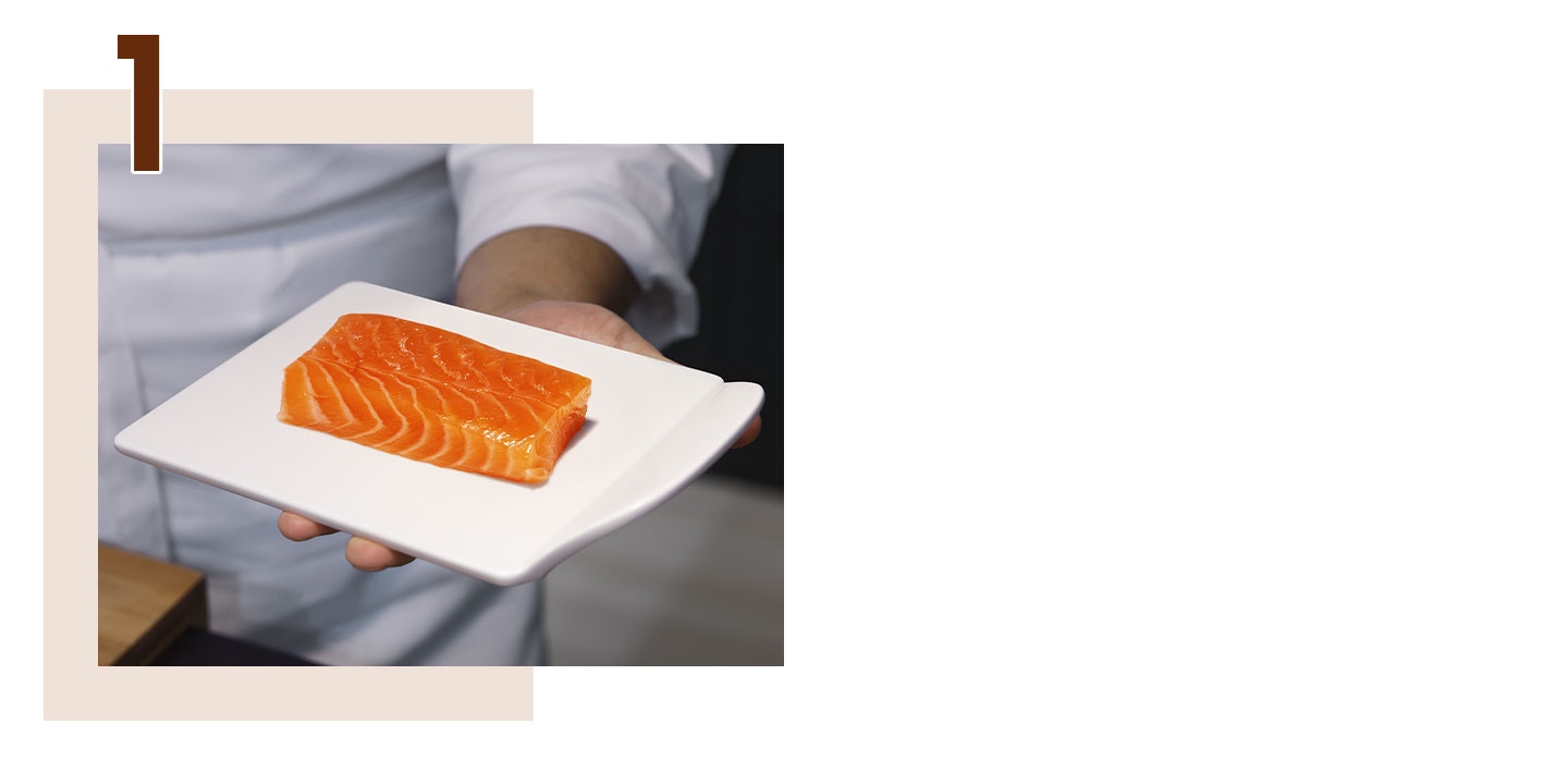 Step 1. A hand holding a plate with a fresh salmon fillet.