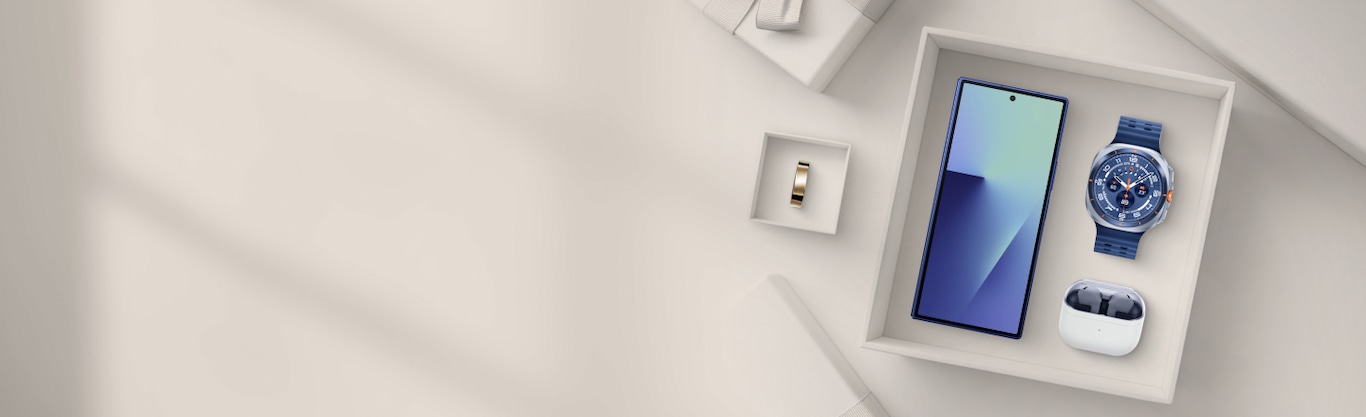 A Galaxy S25 Ultra, a Galaxy Watch Ultra, a pair of Galaxy Buds3, and a Samsung Ring are arranged in gift boxes on a light-coloured surface.