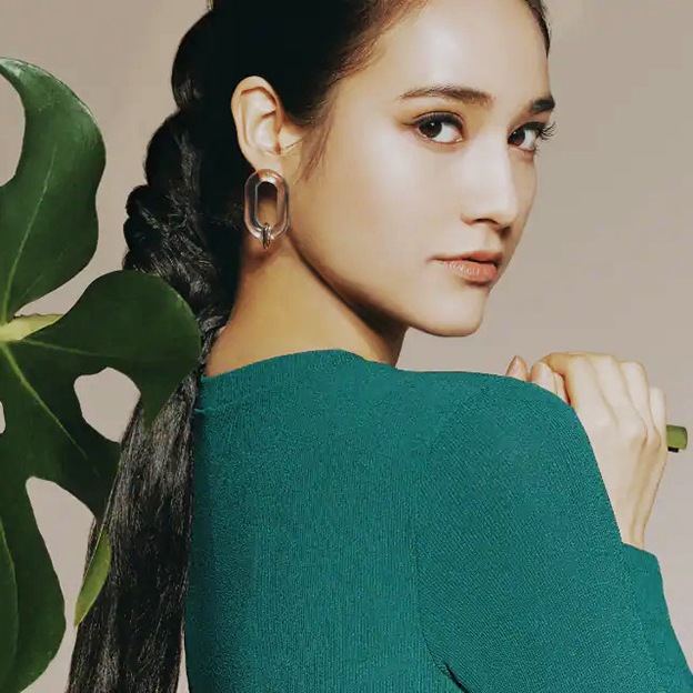 A girl holding a large plant. 