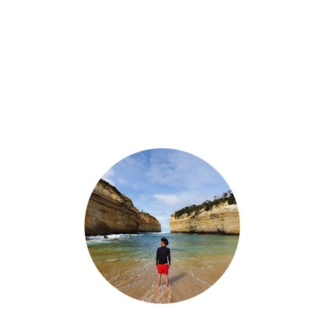 Photo captured by the Galaxy S10+ Ultra Wide Camera of a man standing in a body of water in front of seaside cliffs.