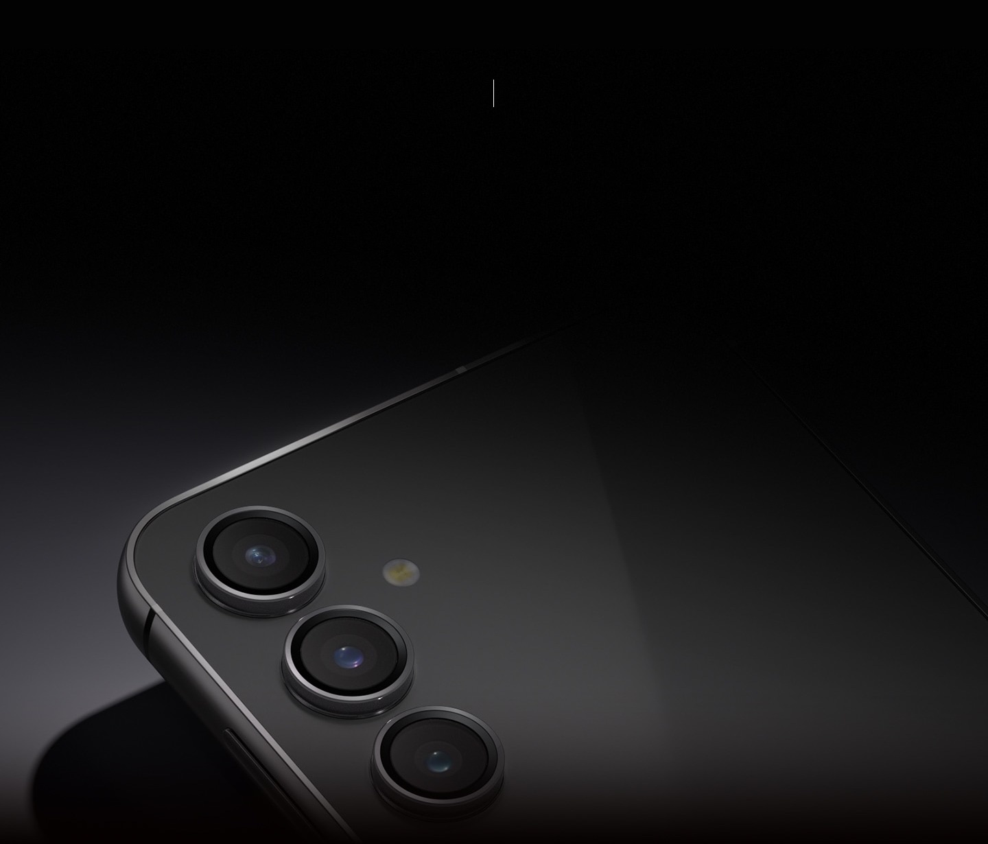 A Galaxy S23 FE device in Graphite lying on its front to show the rear camera in the dim light.