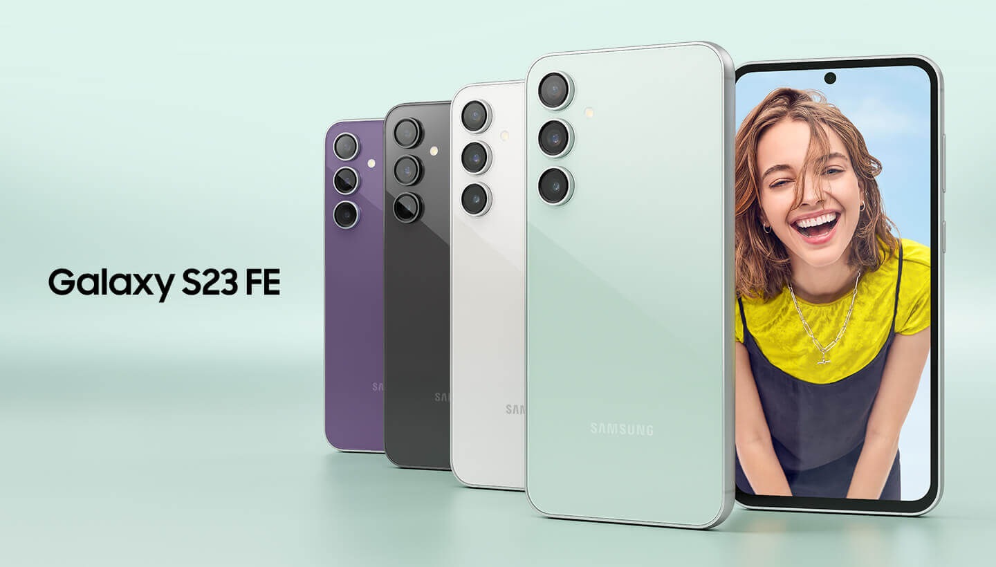 Five Galaxy S23 FE devices in Purple, Graphite, Cream and Mint. Four are seen standing upright from the rear overlapping on top of each other. The other one is seen from the front with a woman up-close onscreen smiling at the camera.
