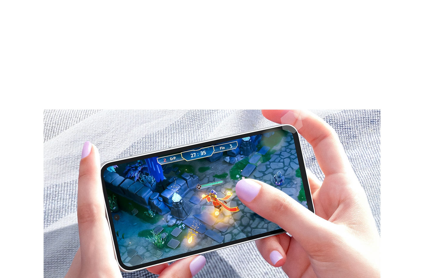 Two hands playing a video game on a Galaxy S23 FE device in bright daylight. The screen shows a …