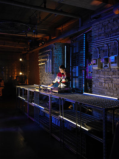 Une photo nocturne claire et colorée d'un DJ dans un salon faiblement éclairé.