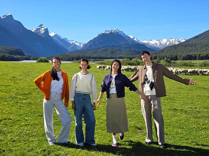 Une photo d'un champ ouvert et de montagnes avec un groupe d'amis au premier plan en optique 2x…
