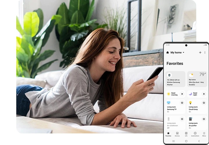 한 여성이 소파에 누워서 웃으며 스마트 폰을보고 있습니다. 전경의 오른쪽에 Galaxy 화면은 다양한 연결된 스마트 홈 장치, 해당 상태 및 기타 루틴을 포함하여 SmartThings App GUI를 보여줍니다