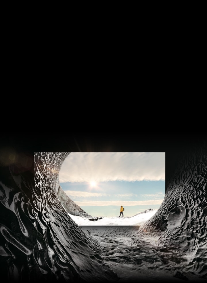 MICRO LED TV is placed inside a mountain cave and is displaying the image of a mountain climber in the sun. The mountain cave blends into the on-screen image to show that the textures of inside and outside the mountain cave are indistinguishable from each other.