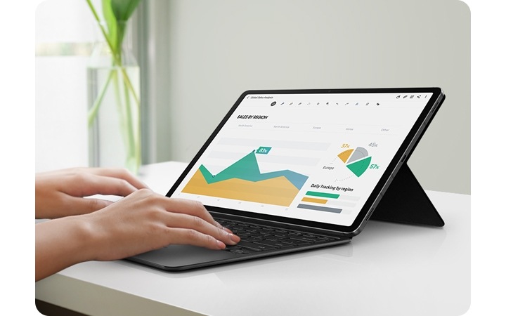 A tablet device is held up with the Book Cover Keyboard at an angle that resembles a laptop. A pair of hands are on the keyboard, busy working on a presentation. 