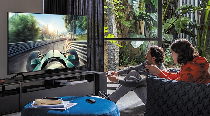 A young man is playing game with QLED TV. Players can complete their gaming experience with its big screen and 4K picture quality with HDR.