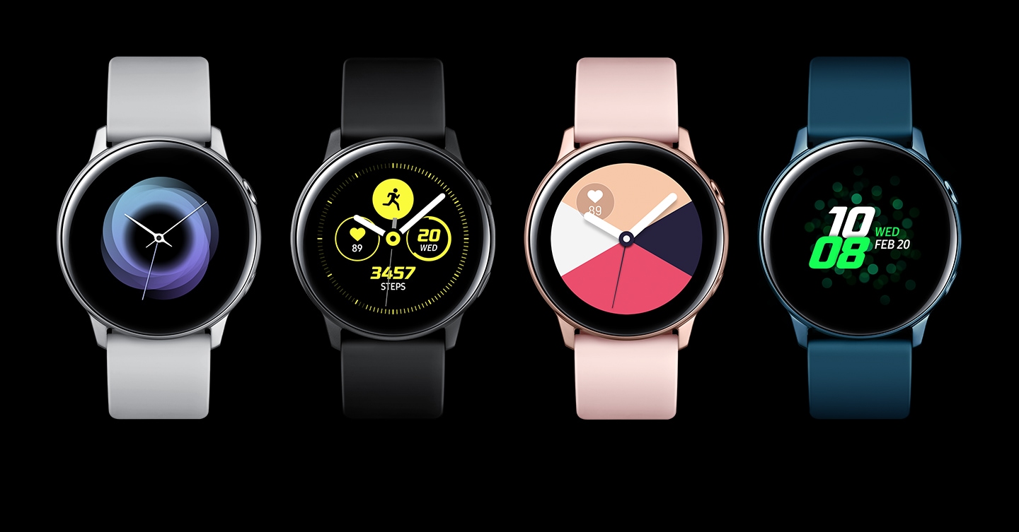 Quatro dispositivos Galaxy Watch Active enfileirados, lado a lado. O primeiro com uma pulseira prata, o segundo com uma pulseira preta, o terceiro com uma pulseira rosa e o último com uma pulseira verde.