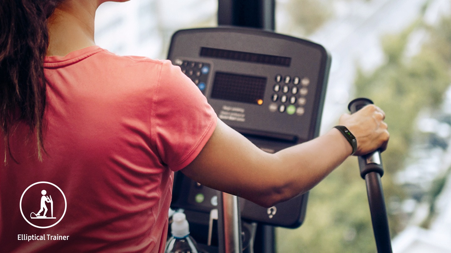 You can see a close-up of a woman on a cross trainer with a black Galaxy Fit2 on her wrist.