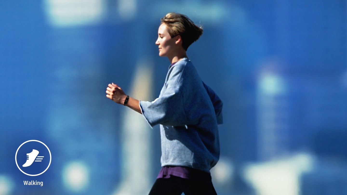 A woman does a walking workout while wearing the Galaxy Fit2 on her left wrist.