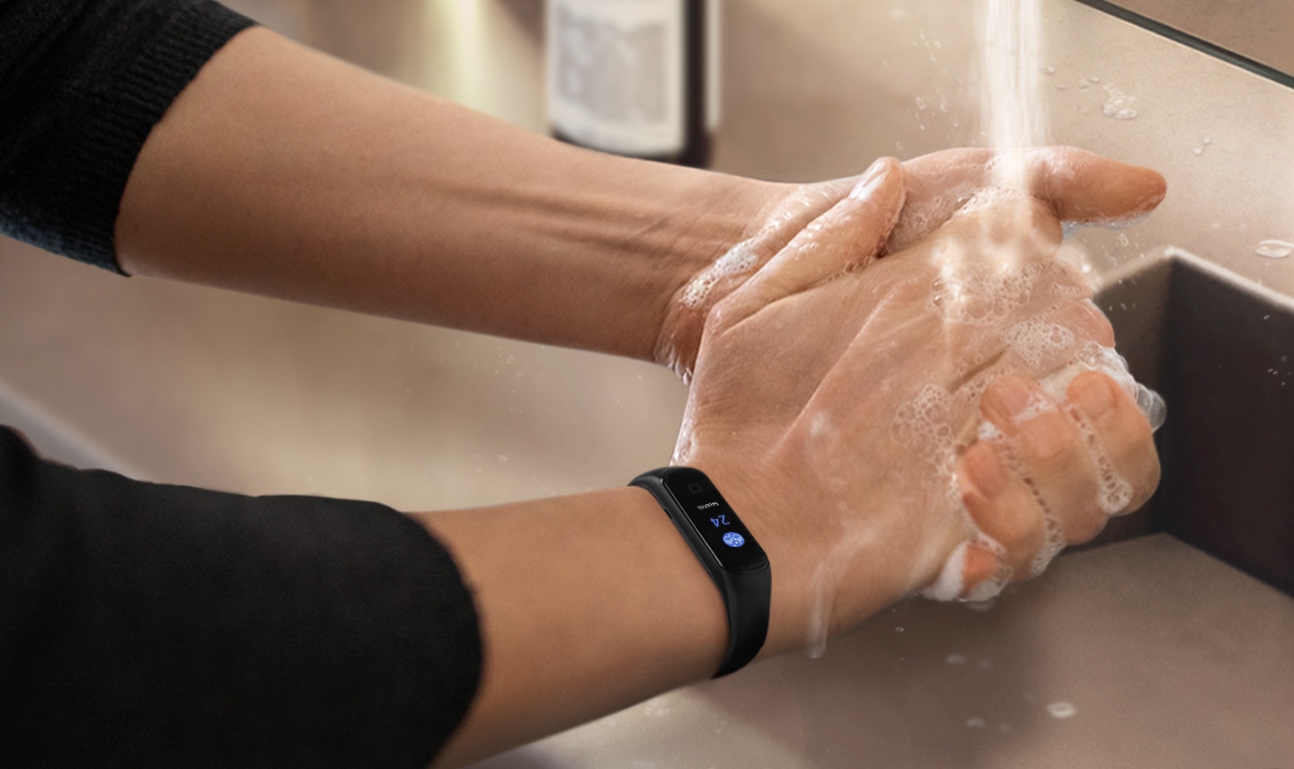 You can see a close-up of a person washing their hands with a black Galaxy Fit2 on their wrist that shows a countdown.