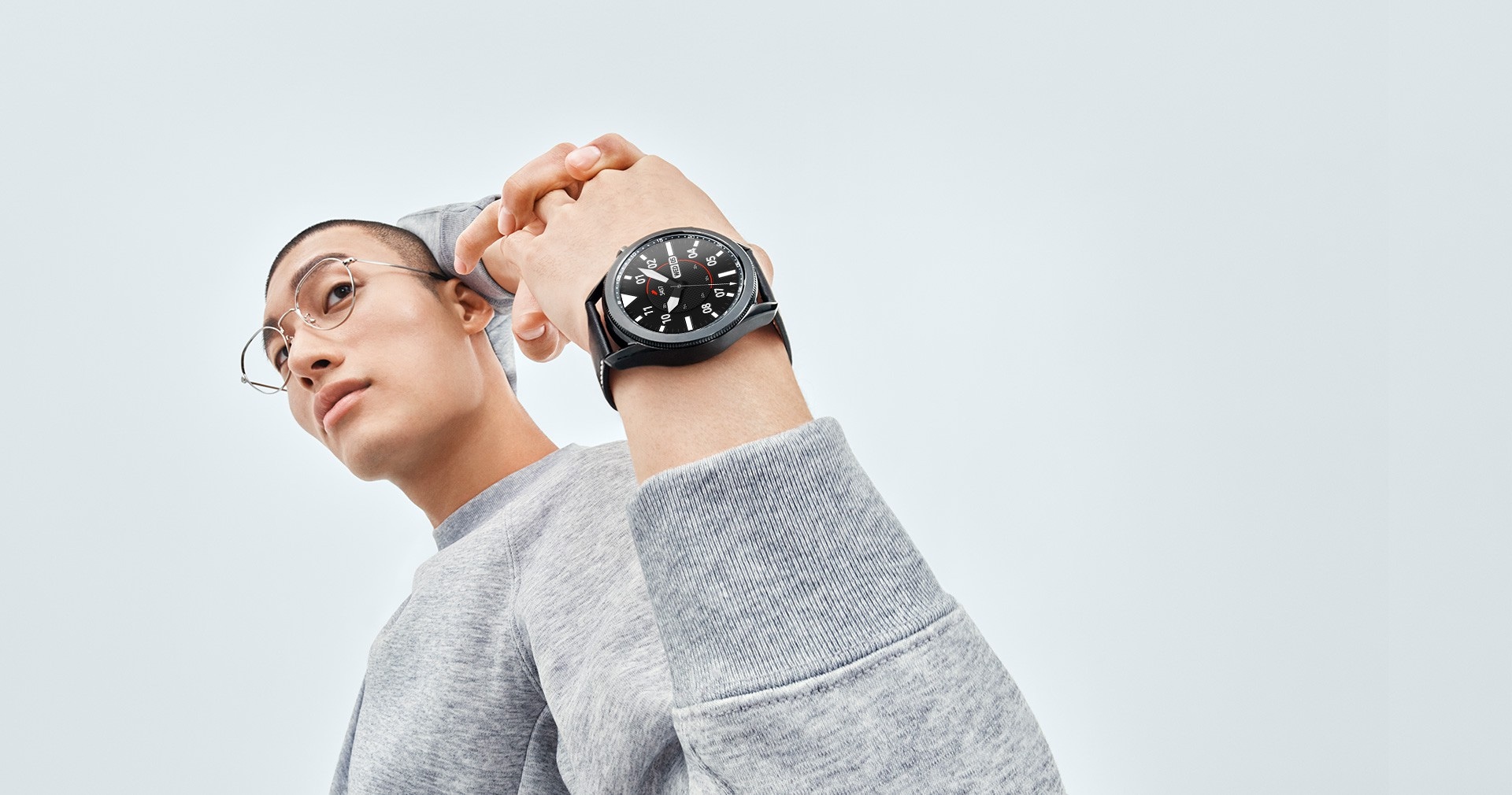 Un hombre estira sus brazos detrás de su espalda, mostrando un Galaxy Watch3 de color Mystic Black en su muñeca con una esfera Sporty Classic.