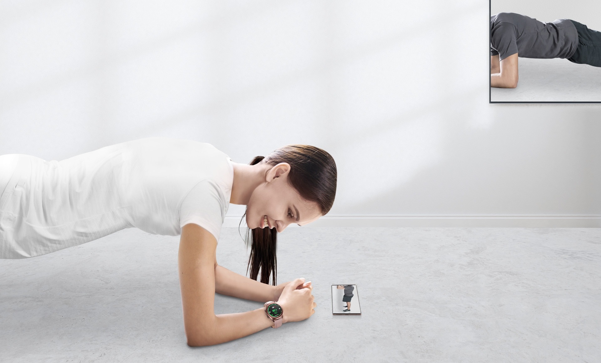 Une femme en position de planche suit un programme d'entranement  domicile qui est diffus depuis un smartphone Galaxy sur le tlviseur. La Galaxy Watch3 45 mm en Mystic Bronze est connecte pour mesurer sa frquence cardiaque.