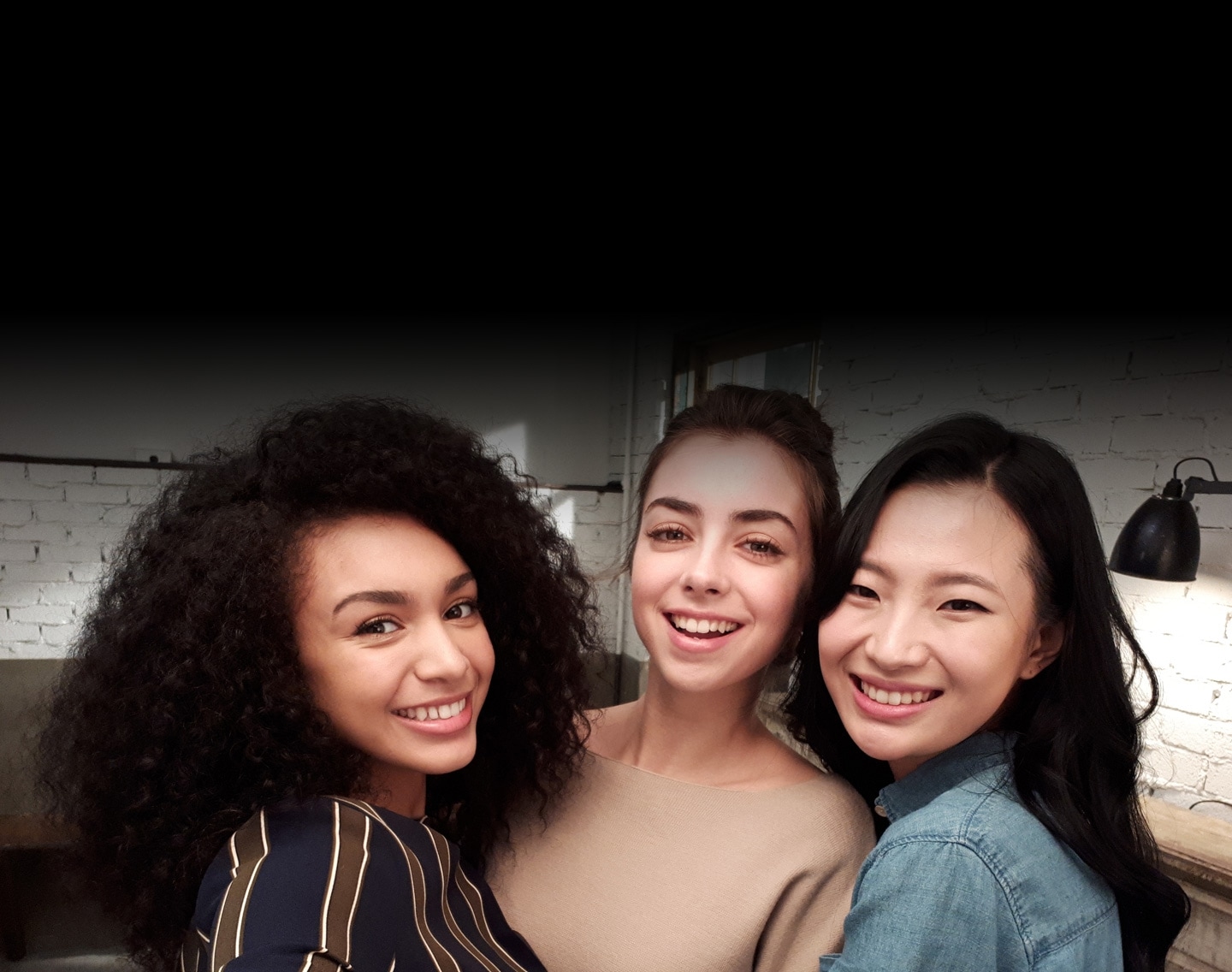 Selfie image of three women taken in low-light to show the advanced camera functionality of the Galaxy A5 (2017).