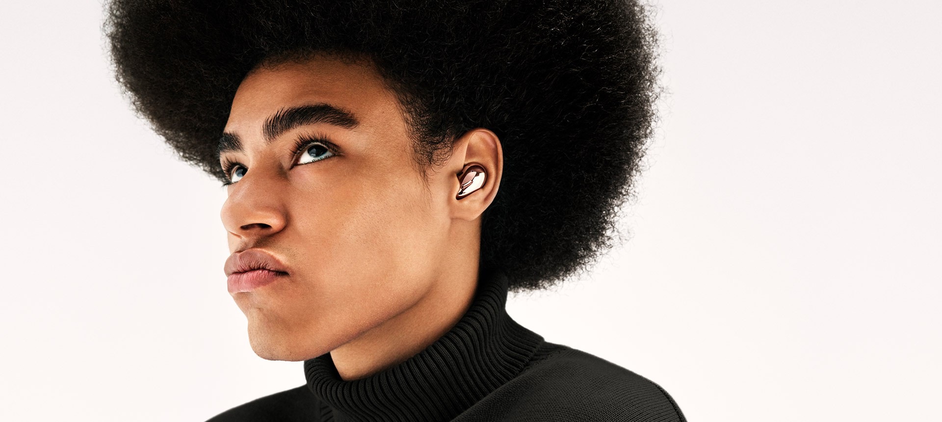 מבט חלקי על איש עם אפרו המרכיב Galaxy Buds Live בגוון ארד. המסך מתקרב לקלוז-אפ על אוזנו.