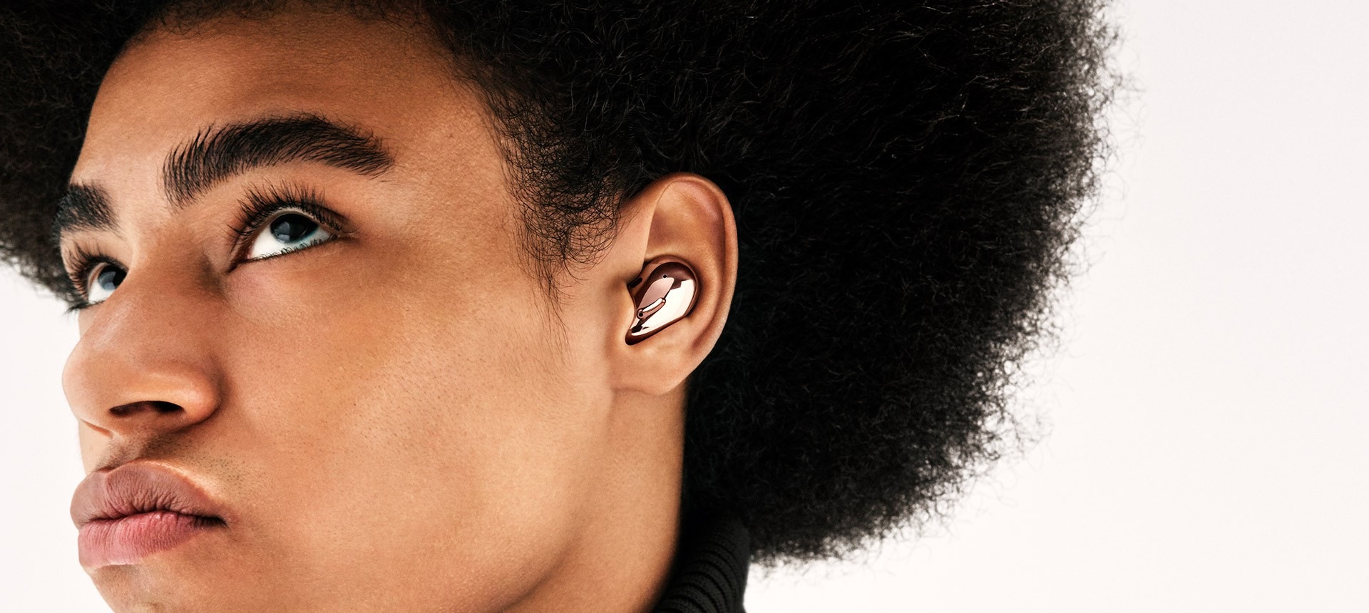 מבט חלקי על איש עם אפרו המרכיב Galaxy Buds Live בגוון ארד. המסך מתקרב לקלוז-אפ על אוזנו.
