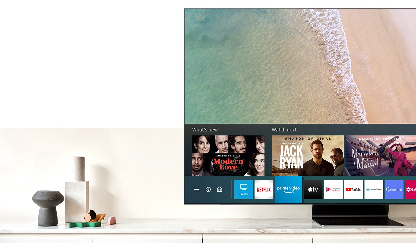 Samsung QLED TV is showing Smart Hub, Samsung Smart TV platform, on the screen. Smart TV powered by Tizen logo is under the TV.