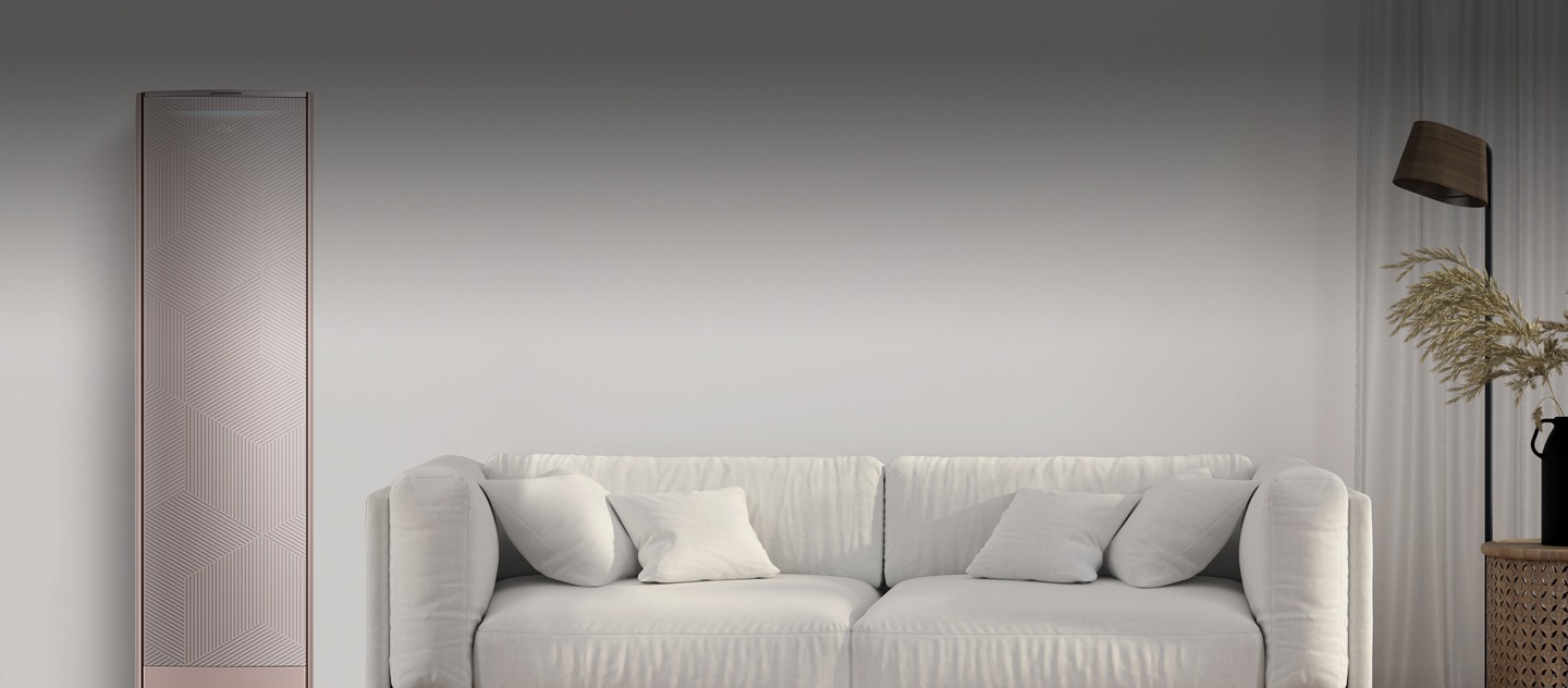 غرفة جلوس مع أريكة بيضاء في المنتصف ومصباح ونبتة على اليمين ومكيف هواء ذكي على اليسار.