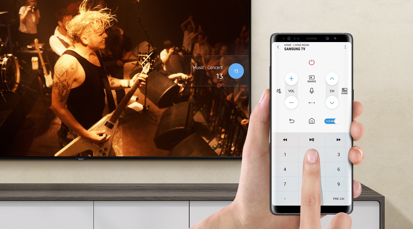 Função de controle remoto no celular pelo aplicativo SmartThings. Na tela da Smart TV, uma banda de rock está fazendo um show.